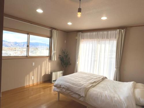 a bedroom with a bed and a large window at Cozy House Azumino in Azumino