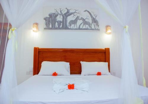 a bedroom with a white bed with orange flowers on it at Datch Hideaway in Kiwengwa