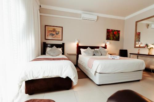 two beds in a room with white walls at Mi Vida Guesthouse in Klerksdorp