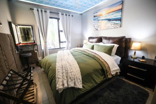 a bedroom with a bed with a green comforter at Heated Pool Luxury Retreat - 7 Min from OR Tambo in Benoni