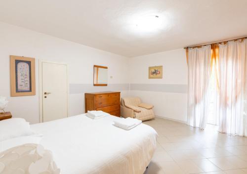 a white bedroom with a bed and a chair at Casa di Montagna tranquilla e spaziosa in Serina