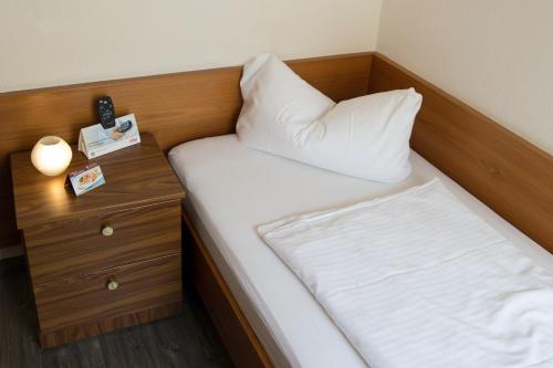 a small bedroom with a bed and a nightstand at Hotel Am Theaterplatz in Bremerhaven