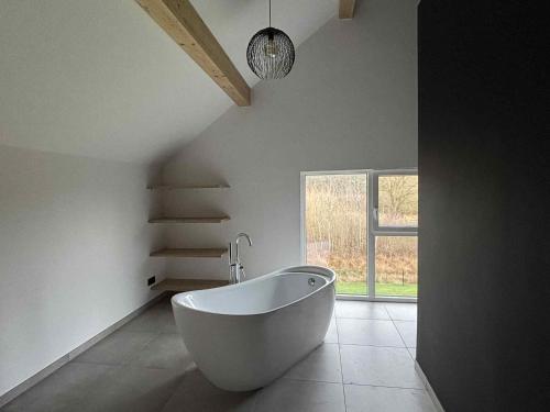 a white bath tub in a room with a window at L'ancien rucher in Hotton