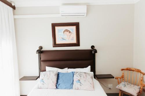 a bedroom with a bed and a chair at Mi Vida Guesthouse in Klerksdorp