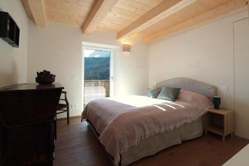 a bedroom with a bed and a window at Casa Tomà Mountain View Cortina in San Vito di Cadore