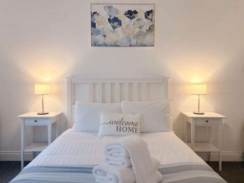 a white bed with a welcome home pillow on it at Euston Road - Beach Apartment 9 in Great Yarmouth