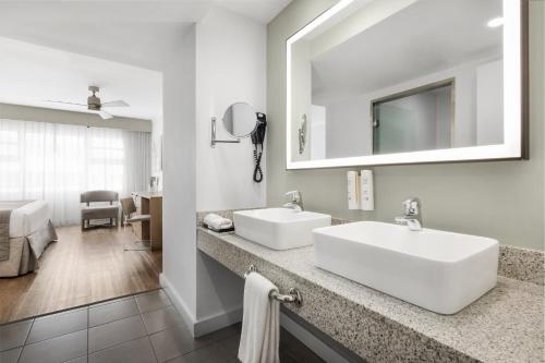 a white bathroom with two sinks and a mirror at Riu Plaza Miami Beach in Miami Beach