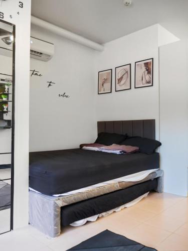 a bed in a white room with two pictures on the wall at LunaVista in Bankal