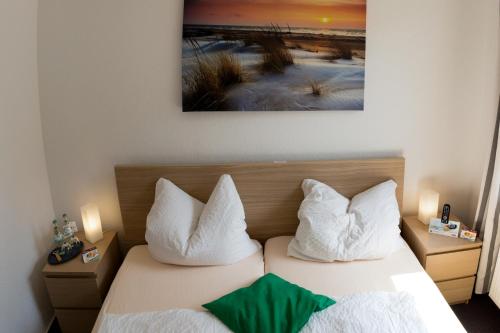 a bedroom with two beds and a painting on the wall at Hotel Am Theaterplatz in Bremerhaven