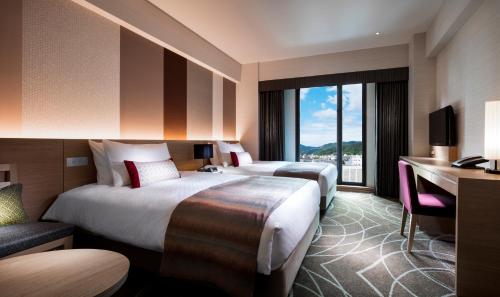 a hotel room with two beds and a desk at RIHGA Royal Hotel Kyoto in Kyoto