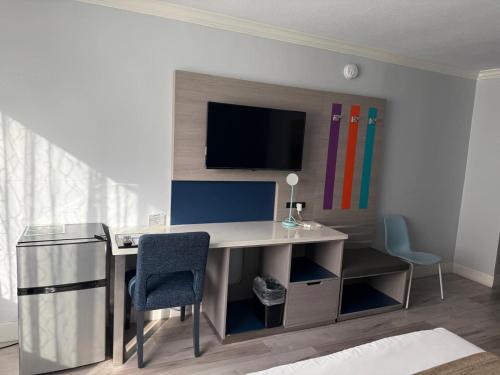 a room with a desk and a tv on a wall at Hometel Suites in Los Angeles