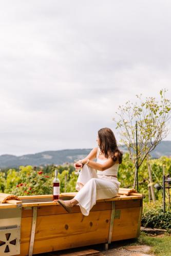a woman sitting on a wooden table with a bottle of wine at SCHILCHERLANDLEBEN - Weingartenhaus in Sankt Stefan ob Stainz