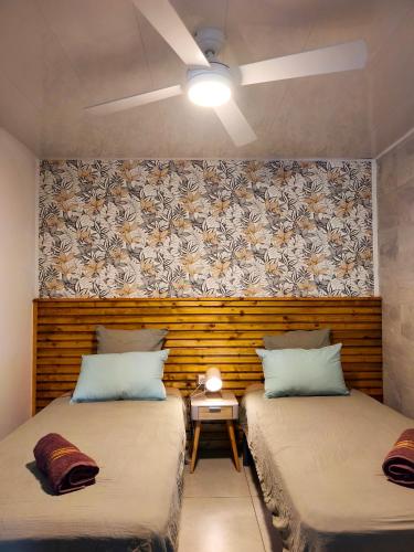two beds sitting next to each other in a room at Ti Kaz Luxuriante - Jacuzzi Privé - Évasion Tropicale & Intimité in Saint-Louis