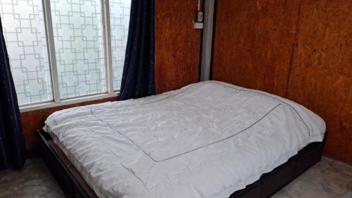 a small bed in a room with two windows at เฮือนอุ้ยดี2 in Ban Khua Nam Chun