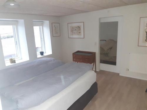 a bedroom with a large bed and a mirror at Stor lejlighed ved togstation in Viborg