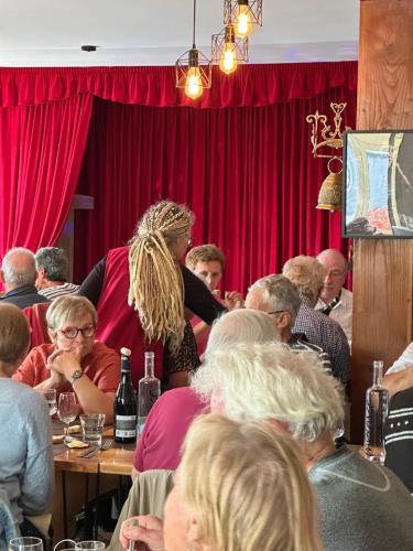 Eine Gruppe von Menschen sitzt an Tischen in einem Raum mit roten Vorhängen. in der Unterkunft Cap'tain Cook in Caurel