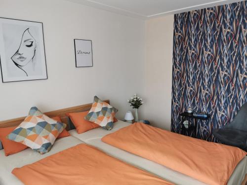 a bedroom with two beds with orange pillows at Ferienwohnung DORFWIESE in NuÃŸbaum