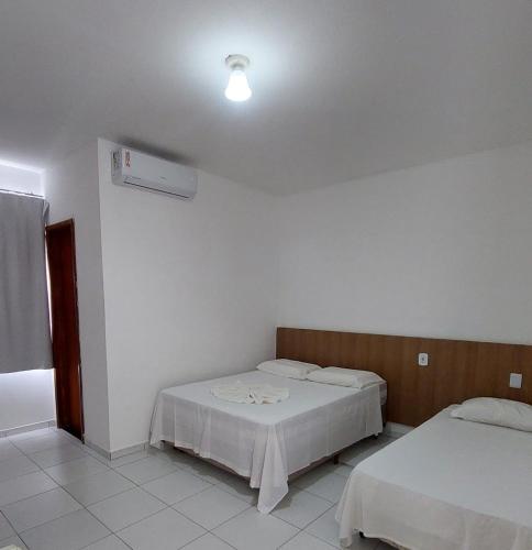 a bedroom with two beds and a ceiling fan at Hotel Ideal in Jequié