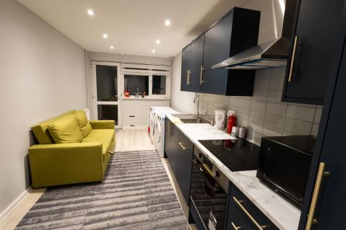 a kitchen with black cabinets and a yellow chair at Modern Rooms - Walk to Kings Cross - Central in London