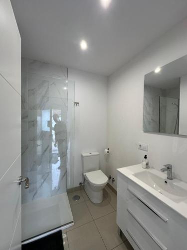 a white bathroom with a toilet and a sink at Apartamento cerca de la playa 8 in Vigo