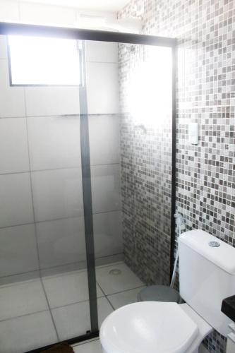 a bathroom with a toilet and a glass shower door at Duplex Apartamento em Casa Caiada in Olinda