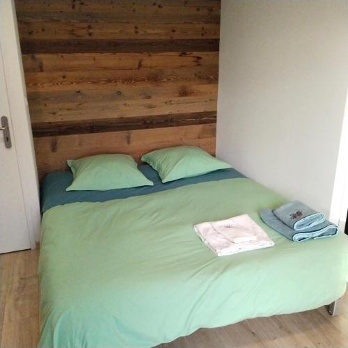 un lit avec des draps et des oreillers verts dans une chambre dans l'établissement Studio Nature, à Marboz