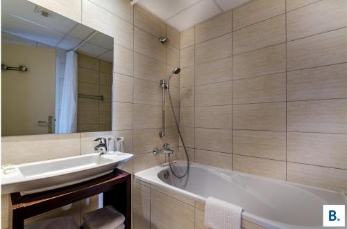 a bathroom with a sink and a tub and a mirror at Hôtel Croix des Bretons - Lourdes Pyrénées in Lourdes