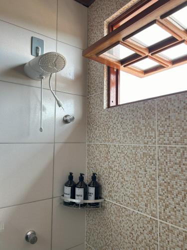 a bathroom with a shower with bottles on a shelf at Bella Casa Ipê 1º andar APA Barra de Mamanguape in Rio Tinto