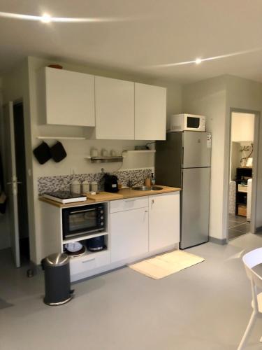 a kitchen with white cabinets and a refrigerator at Au Passe-Temps in Mettray