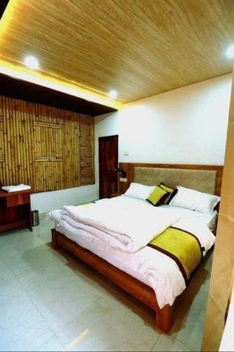 a bedroom with a large bed with a wooden ceiling at The Himalayan Majesty Hotel in Chopta