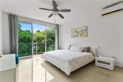 a white bedroom with a bed and a large window at Casa Lula 5-BR Getaway in Riviera Maya in Playa del Carmen