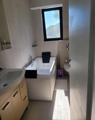 a bathroom with a tub and a sink and a window at La Mer Villa - Entire Cottage in Plomari