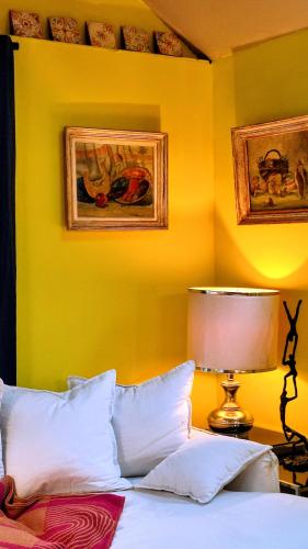 a bedroom with yellow walls and a bed and a lamp at La Demeure du Figuier in Évran