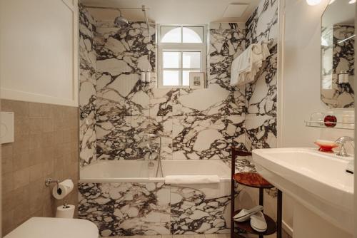a bathroom with a tub and a toilet and a sink at Hotel Villa Bonnie in Knokke-Heist