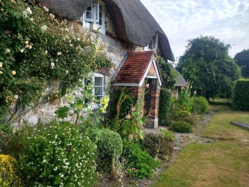 a thatched cottage with a garden in front of it at The Cottage in Fyfield