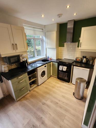 a kitchen with green and white cabinets and a stove at Bank End Cottage in Almondbury