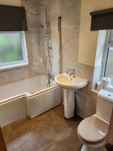 a bathroom with a sink and a tub and a toilet at Bank End Cottage in Almondbury