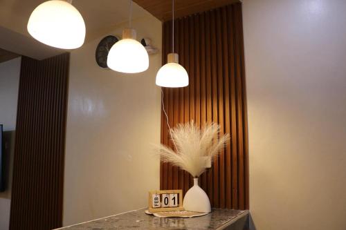 a table with two lights and a vase with feathers at Homestay in Lipa City in Lipa