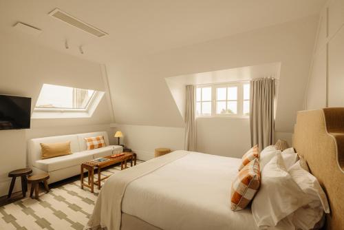 a white bedroom with a bed and a couch at Hotel Villa Bonnie in Knokke-Heist