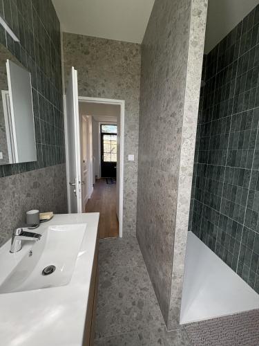 ein Badezimmer mit weißem Waschbecken und grünen Fliesen in der Unterkunft Maison 1880 in Annonay