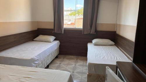 two beds in a room with a window at Pousada Bela Rainha in Aparecida