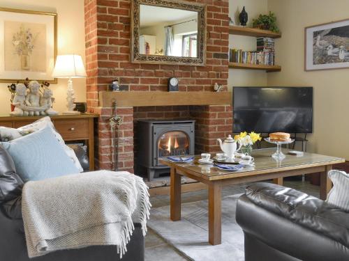 a living room with a table and a fireplace at Riverside Cottage in Costessey