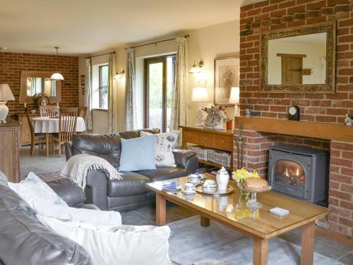 a living room with a couch and a fireplace at Riverside Cottage in Costessey
