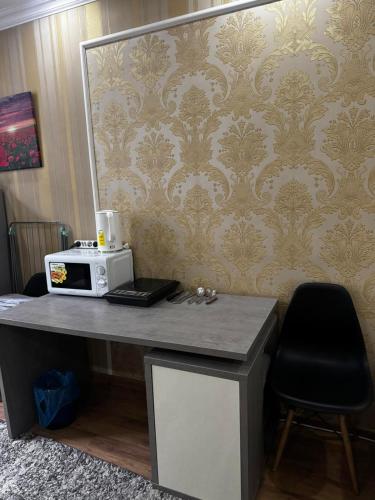 Un escritorio con microondas y una pared con papel pintado. en Hôtel Baldei, en Chişinău
