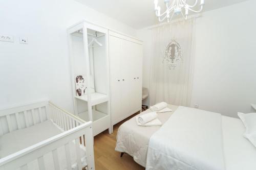 a white bedroom with two beds and a mirror at KLM holiday home in Rupalj