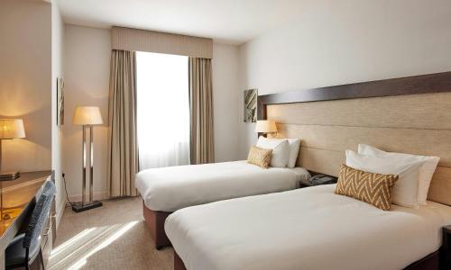 a hotel room with two beds and a television at Thistle London Holborn in London
