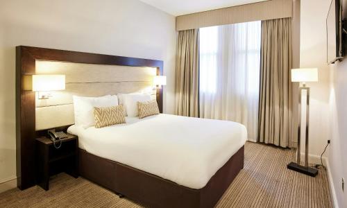 a hotel room with a large bed and a window at Thistle London Holborn in London