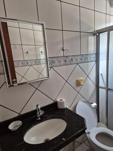 a bathroom with a sink and a toilet and a mirror at Chalé dos Marques in Caldas Novas