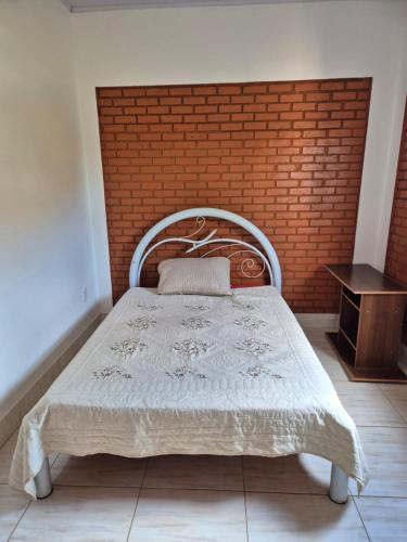 a bed in a room with a brick wall at Chalé dos Marques in Caldas Novas