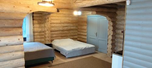 a bedroom with two beds and a door in a log wall at Loft Bucovina in Gura Humorului